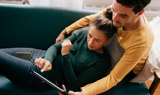 Married couple reviewing credit score on a tablet together.
