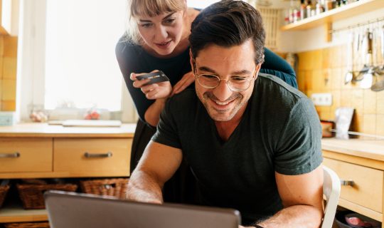 Woman leaning over man’s shoulder to look at computer