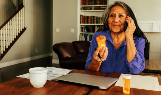 Woman on the phone holding a prescription bottle.
