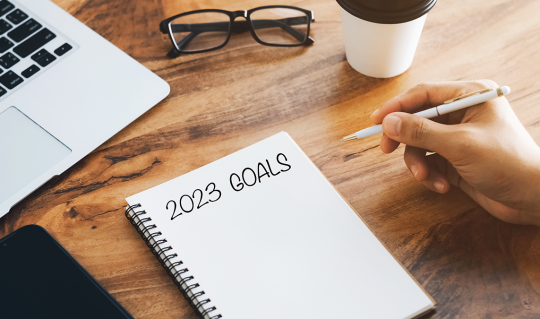 Writing 2023 financial goals in a notebook